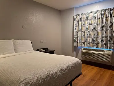 a bedroom with a bed and a window with a air conditioner at Motel 6-Simi Valley, CA in Simi Valley