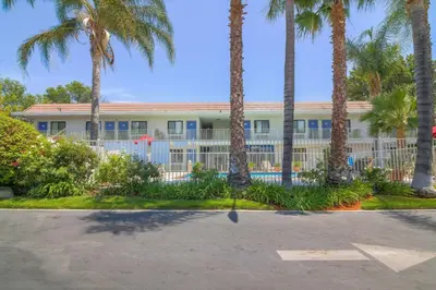 a building with palm trees and a fence at Motel 6-Simi Valley, CA in Simi Valley