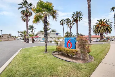 a sign sitting in the grass next to palm trees at Motel 6-Ventura, CA - Beach in Ventura