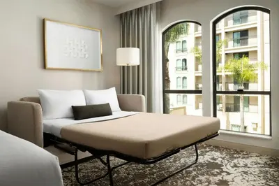 a bedroom with a bed and a couch and a window at Courtyard by Marriott Los Angeles Pasadena Old Town in Pasadena