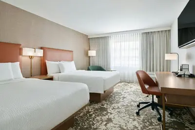 a hotel room with two beds and a desk at Courtyard by Marriott Los Angeles Pasadena Old Town in Pasadena