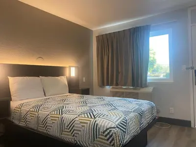 a bedroom with a bed with a large window at Motel 6-San Bernardino, CA - South in San Bernardino