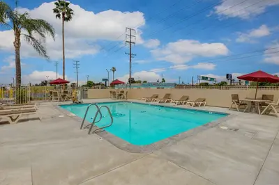 a swimming pool with chairs and umbrellas at a resort at Motel 6-San Bernardino, CA - South in San Bernardino