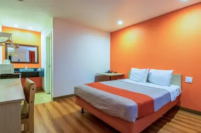 a bedroom with a bed with an orange wall at Motel 6-Bakersfield, CA - Airport in Bakersfield