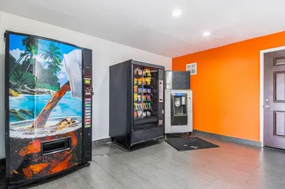 a soda machine in a room with an orange wall at Motel 6-Bakersfield, CA - Airport in Bakersfield