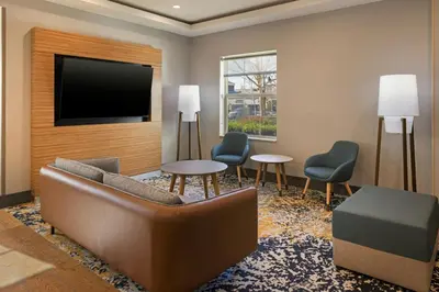 a lobby with a couch and a tv and chairs at TownePlace Suites by Marriott Ontario Airport in Rancho Cucamonga