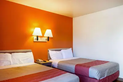 two beds in a hotel room with orange walls at Motel 6-Mojave, CA in Mojave