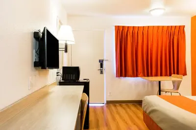 a hotel room with a bed and an orange curtain at Motel 6-Mojave, CA in Mojave