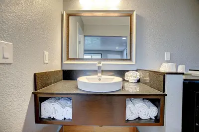 a bathroom with a sink and a mirror and towels at Welcome Inn San Bernardino/ Colton in Colton