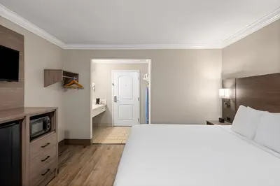 a hotel room with a large bed and a bathroom at Solara Inn and Suites in Anaheim