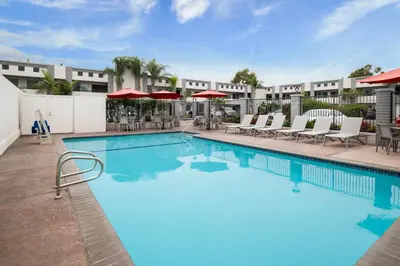 a pool at a hotel with chairs and umbrellas at Solara Inn and Suites in Anaheim
