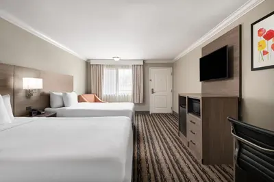 a hotel room with two beds and a flat screen tv at Solara Inn and Suites in Anaheim