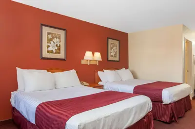 two beds in a hotel room with red walls at America's Best Value Inn & Suites Bakersfield Central in Bakersfield