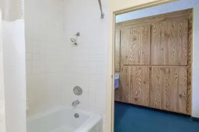 a bathroom with a tub and a shower with a wooden door at America's Best Value Inn & Suites Bakersfield Central in Bakersfield