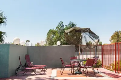 a patio with chairs and a table and an umbrella at America's Best Value Inn & Suites Bakersfield Central in Bakersfield