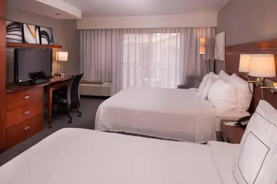 a hotel room with two beds and a desk and a television at Courtyard by Marriott Thousand Oaks Ventura County in Thousand Oaks