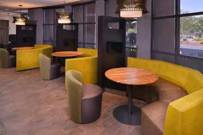 a restaurant with yellow chairs and tables and windows at Courtyard by Marriott Thousand Oaks Ventura County in Thousand Oaks