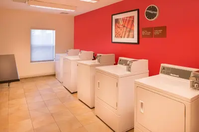 a laundry room with white washers and dryers against a red wall at TownePlace Suites by Marriott Thousand Oaks Ventura County in Thousand Oaks