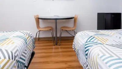 two chairs and a table in a room with two beds at Motel 6 Ontario, CA - Airport in Ontario