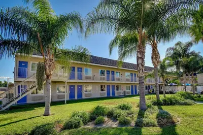 a building with blue doors and palm trees at Motel 6-Riverside, CA - South in Riverside