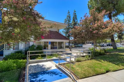 a building with trees and benches in front of it at Motel 6-San Dimas, CA - Los Angeles in San Dimas