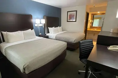 a hotel room with two beds and a desk at Quality Inn Ontario Airport Convention Center in Ontario