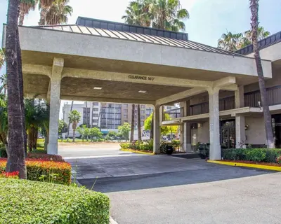 a large building with a parking lot with palm trees at Quality Inn Riverside near UCR and Downtown in Riverside
