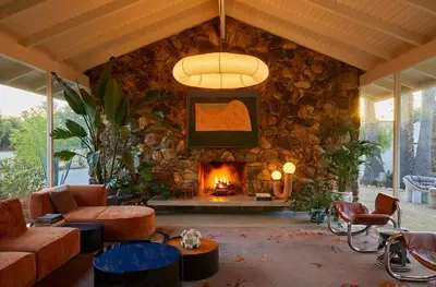 a living room with a stone wall with a fireplace at The Capri Hotel in Ojai