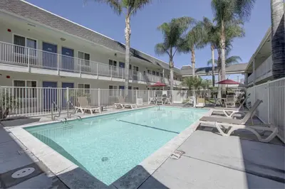 a swimming pool in front of a building with palm trees at Motel 6-Westminster, CA - North in Westminster