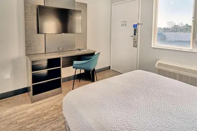 a bedroom with a bed and a desk with a television at Motel 6-Lancaster, CA in Lancaster