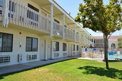 a building with a green lawn in front of it at Vagabond Inn Buttonwillow North I-5 in Buttonwillow