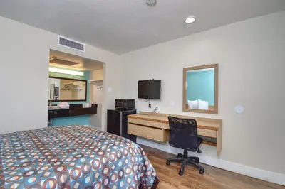 a hotel room with a bed and a desk and a computer at Vagabond Inn Buttonwillow North I-5 in Buttonwillow
