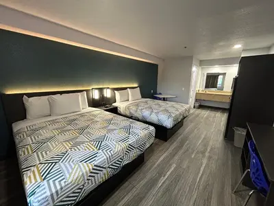 a hotel room with two beds and a desk at Studio 6 Bakersfield, CA South in Bakersfield