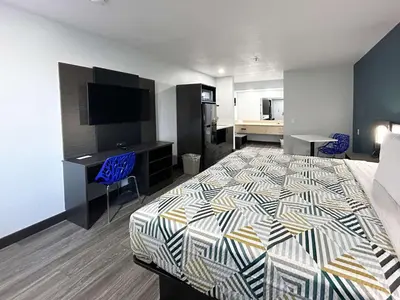 a bedroom with a bed and a desk with a television at Studio 6 Bakersfield, CA South in Bakersfield