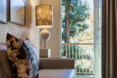 a living room with a couch and a lamp and a window at Chamberlain West Hollywood in Los Angeles
