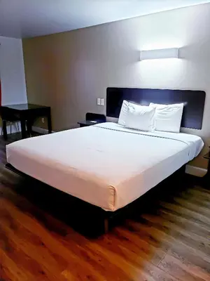 a large white bed in a room with a wooden floor at Motel 6-Hesperia, CA - West Main Street I-15 in Hesperia