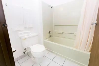 a white bathroom with a toilet and a bath tub at Morada Inn in Anaheim