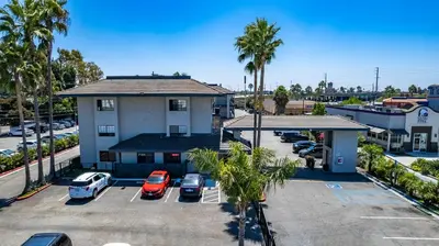 an apartment building with cars parked in a parking lot at Morada Inn in Anaheim