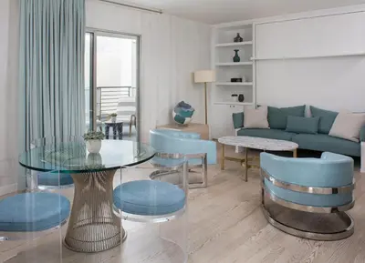 a living room with a glass table and blue chairs at Avalon Hotel Beverly Hills, a Member of Design Hotels in Los Angeles