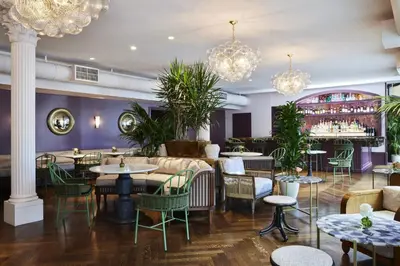 a restaurant with tables and chairs and chandeliers at The Aster in Los Angeles