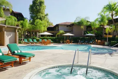 a swimming pool with chaise lounge chairs and tables at DoubleTree by Hilton Claremont in Claremont