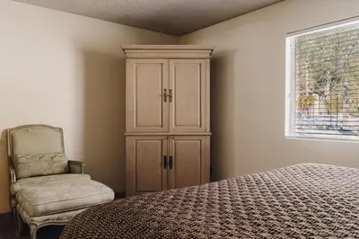 a bedroom with a bed and a chair and a cabinet at Vintage Lakeside Inn in Big Bear Lake