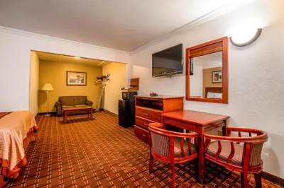 a hotel room with a bed and a desk and a mirror at Regency Inn & Suites Downey in Downey