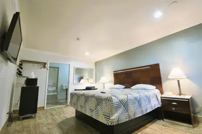 a bedroom with a large bed and a mirror at Welcome Inn Corona in Corona