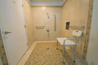 a bathroom with a shower and a chair in it at Welcome Inn Corona in Corona
