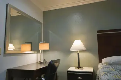 a bedroom with a desk and a bed and a mirror at Welcome Inn Corona in Corona