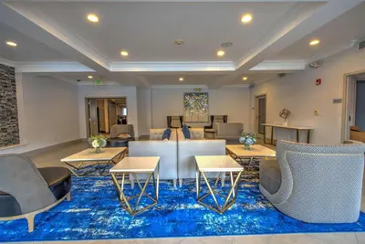 a lobby with couches and tables and chairs on a blue rug at Best Western Plus Media Center Inn & Suites in Burbank