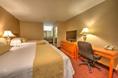 a hotel room with two beds and a desk with a computer at Burbank Inn and Suites in Burbank