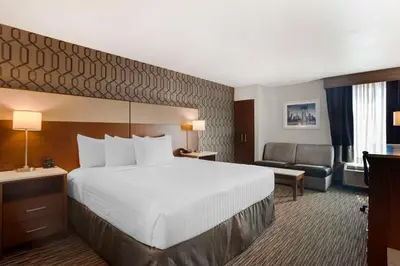 a hotel room with a large bed and a chair at Best Western Plus Commerce Hotel in Los Angeles