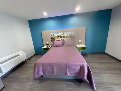 a bedroom with a large bed with a purple bedspread at Hi-Way Host Motel in Pasadena